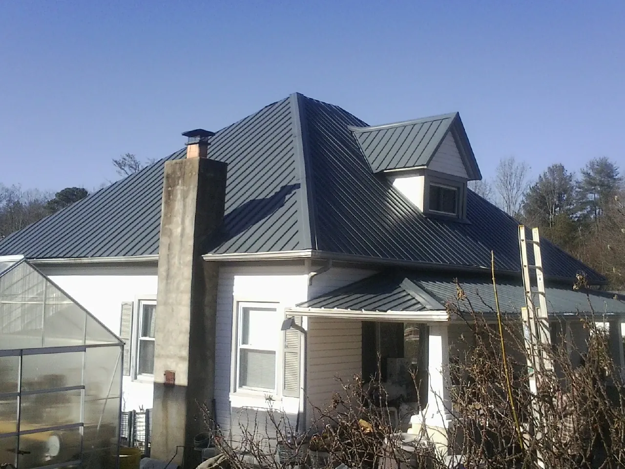 Dark blue standing seam metal roof on a white farmhouse with dormer — Slate & Tile Roof Repair by Roofing Brothers in Blountville