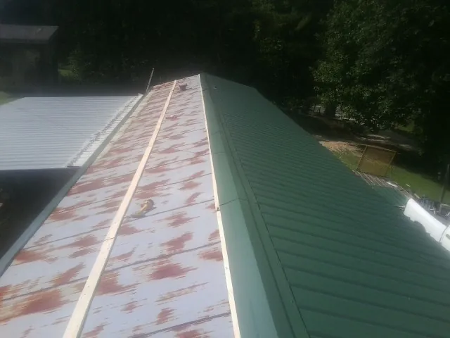 Old rusted panels beside newly installed green metal roofing — Wind Damage Roof Repair by Roofing Brothers in Blountville