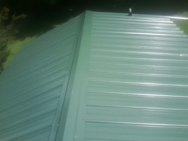 New green metal panels meeting at the ridge of a roof — Flat Roof Repair work by our crew in Blountville