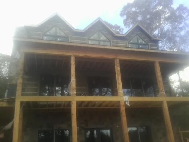 Dormers and porch framing on a large log home under construction — Roof Coating work by our crew in Blountville
