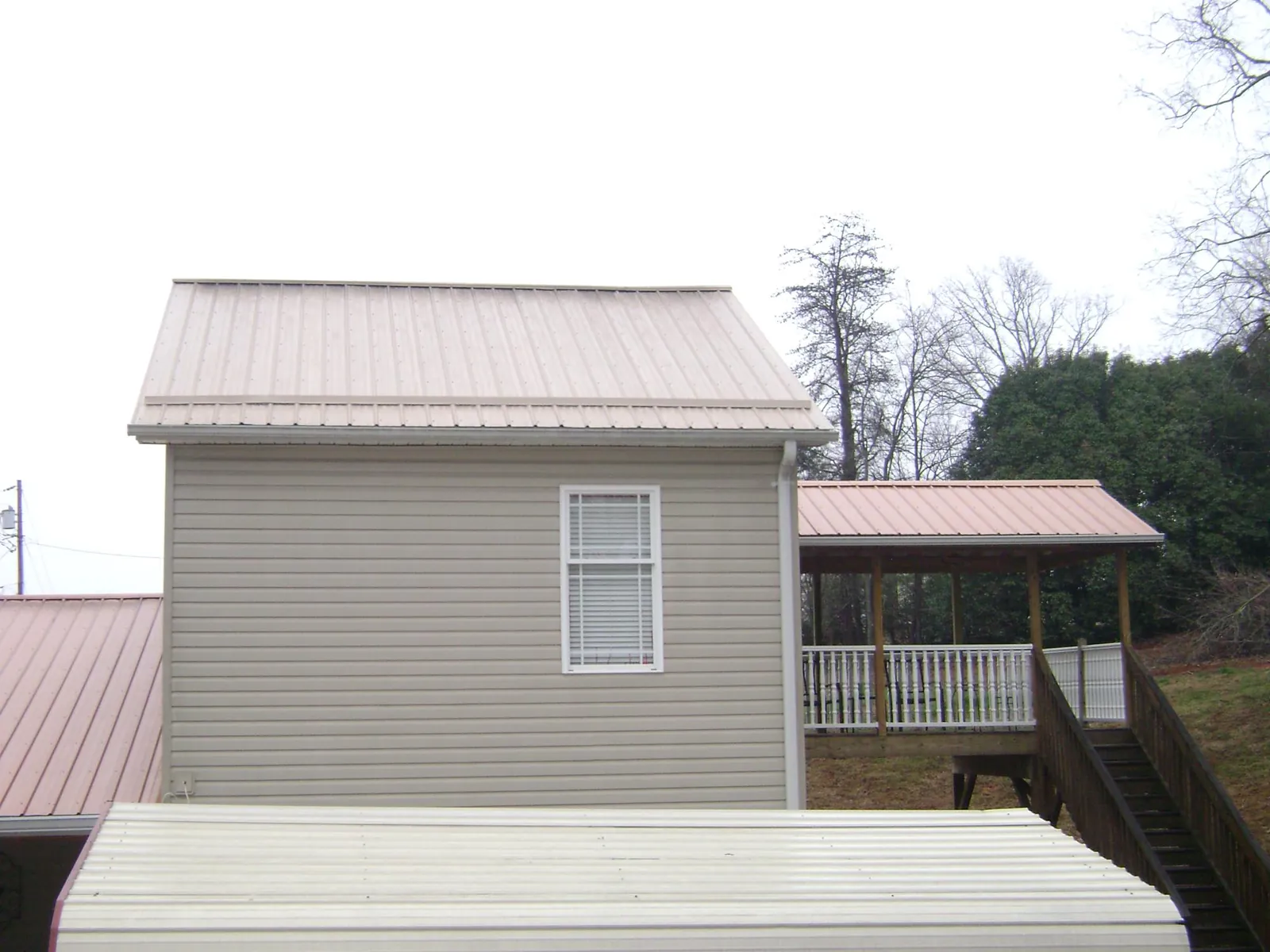 Tan metal roofs on a two story addition and attached porch, from a Roof Replacement job in Blountville