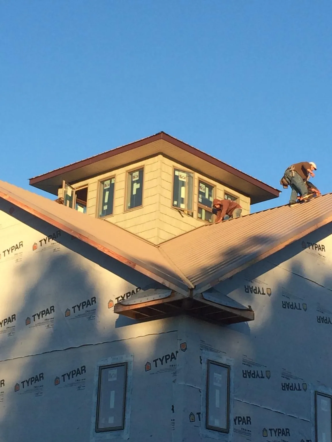 Roofers working around a rooftop cupola on a new metal roof at sunset — Roof Waterproofing in Blountville by Roofing Brothers